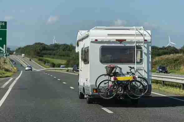 Camping-car avec vélos à l'arrière sur une autoroute ensoleillée.