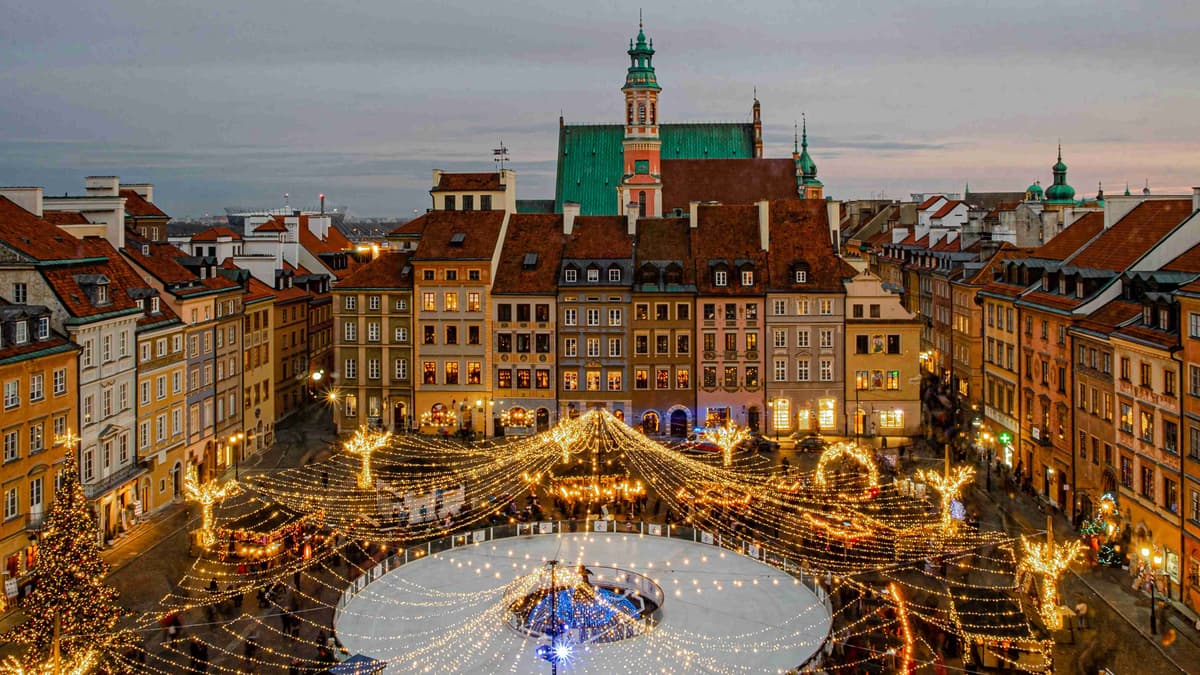 أضواء سوق عيد الميلاد في ساحة المدينة القديمة في وارسو مع خلفية القلعة الملكية