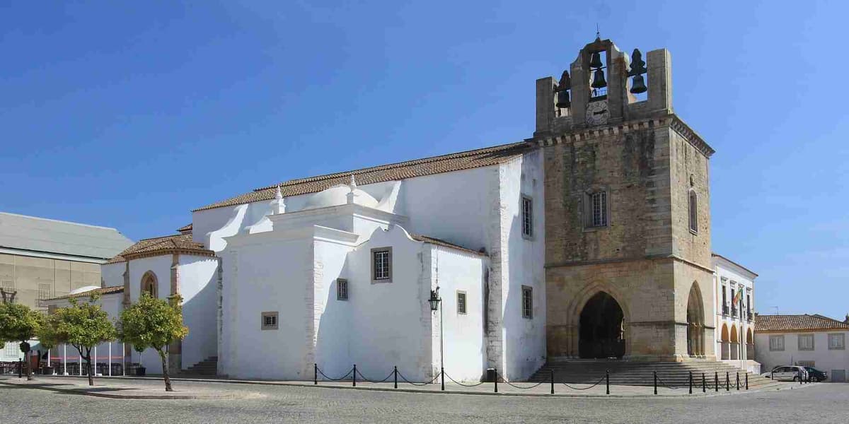 White historical building faro cathedral with a bell tower on a sunny day.