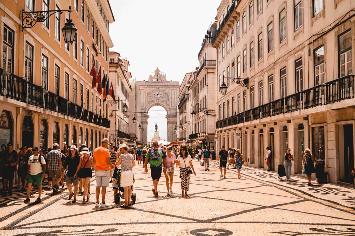 Lisbon street with pedestrians, historic buildings, and arch monument