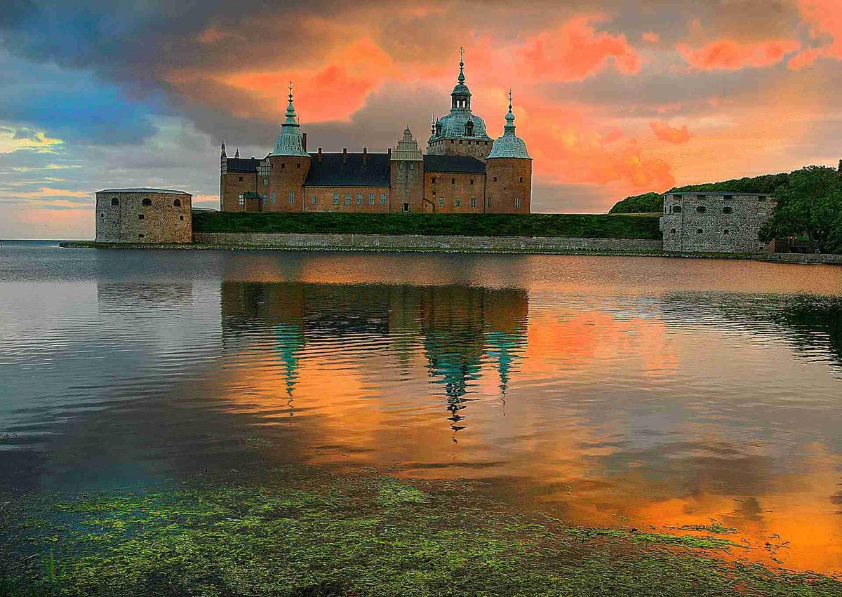 غروب الشمس في قلعة كالمار في السويد مع انعكاسات السماء الزاهية.