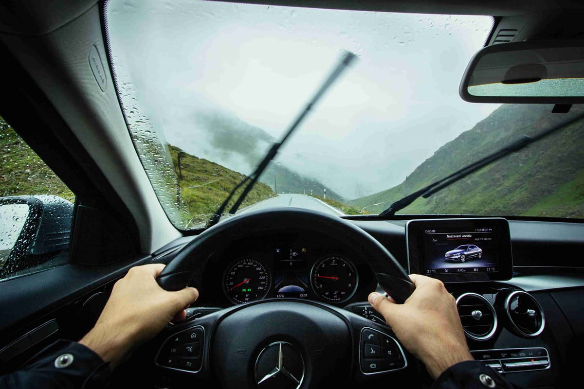 وجهة نظر السائق في سيارة مرسيدس على طريق جبلي ضبابي مع هطول الأمطار في ممر ستلفيو، سويسرا.
