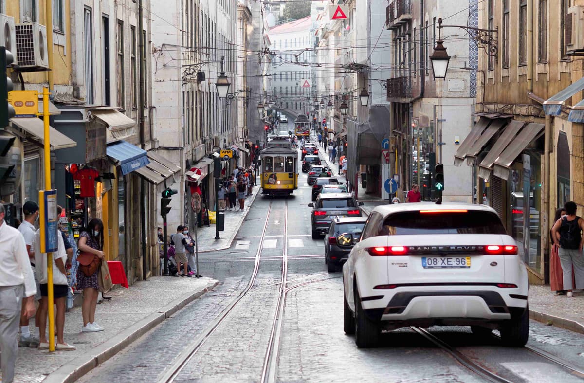 busy street in Lisbon with a tram, cars, and pedestrians.