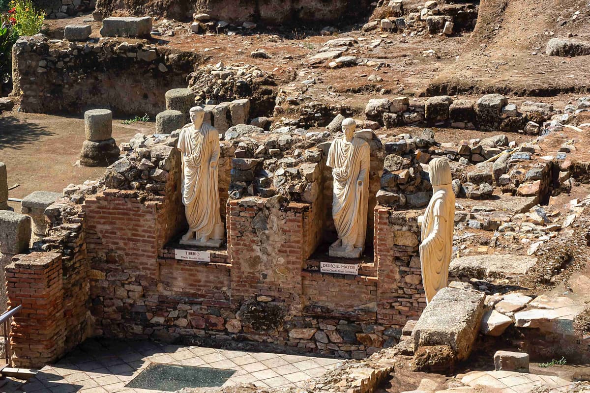 Tiberius and Drusus statues amid ancient Roman ruins.