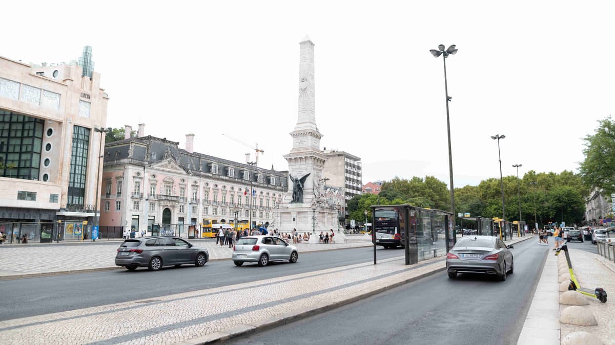 ساحة المدينة مع النصب التذكاري والسيارات في لشبونة، البرتغال.