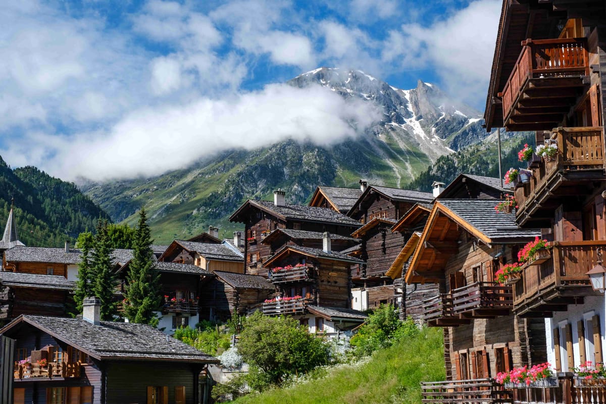 Alpine chalets with mountain backdrop under blue sky.