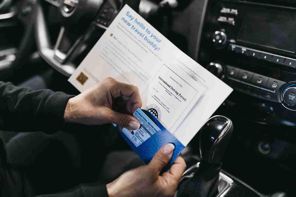 A person holding an International Driver's Permit in a car.