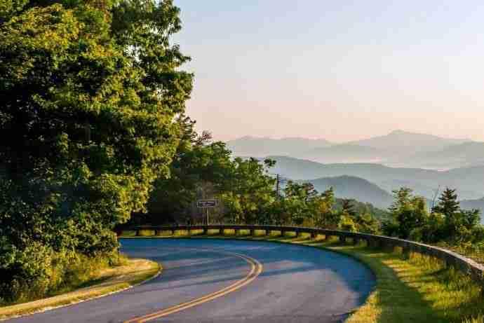 Curved road with mountain views at sunrise.