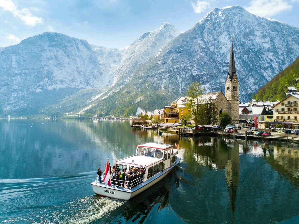 Alppien kylä kirkon ja veneen kanssa järvellä