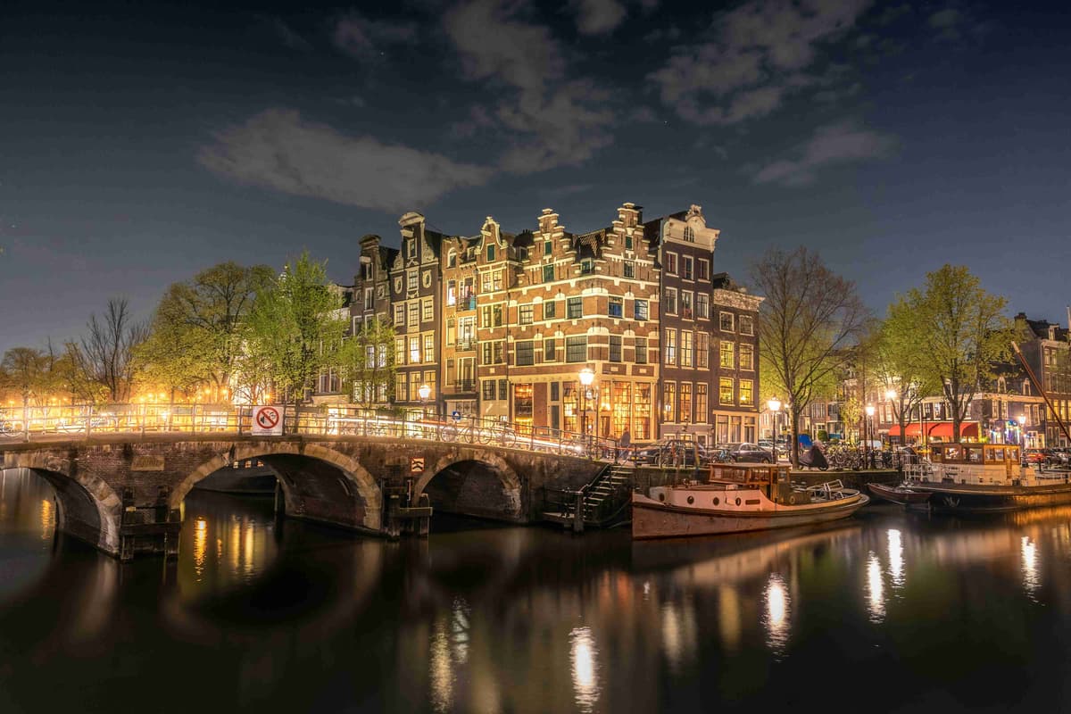 Amsterdam Canal at Night with Illuminated Bridge and Buildings