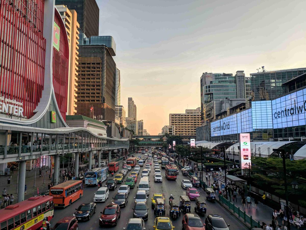 Busy street at dusk with cars and city buildings in Bangkok.