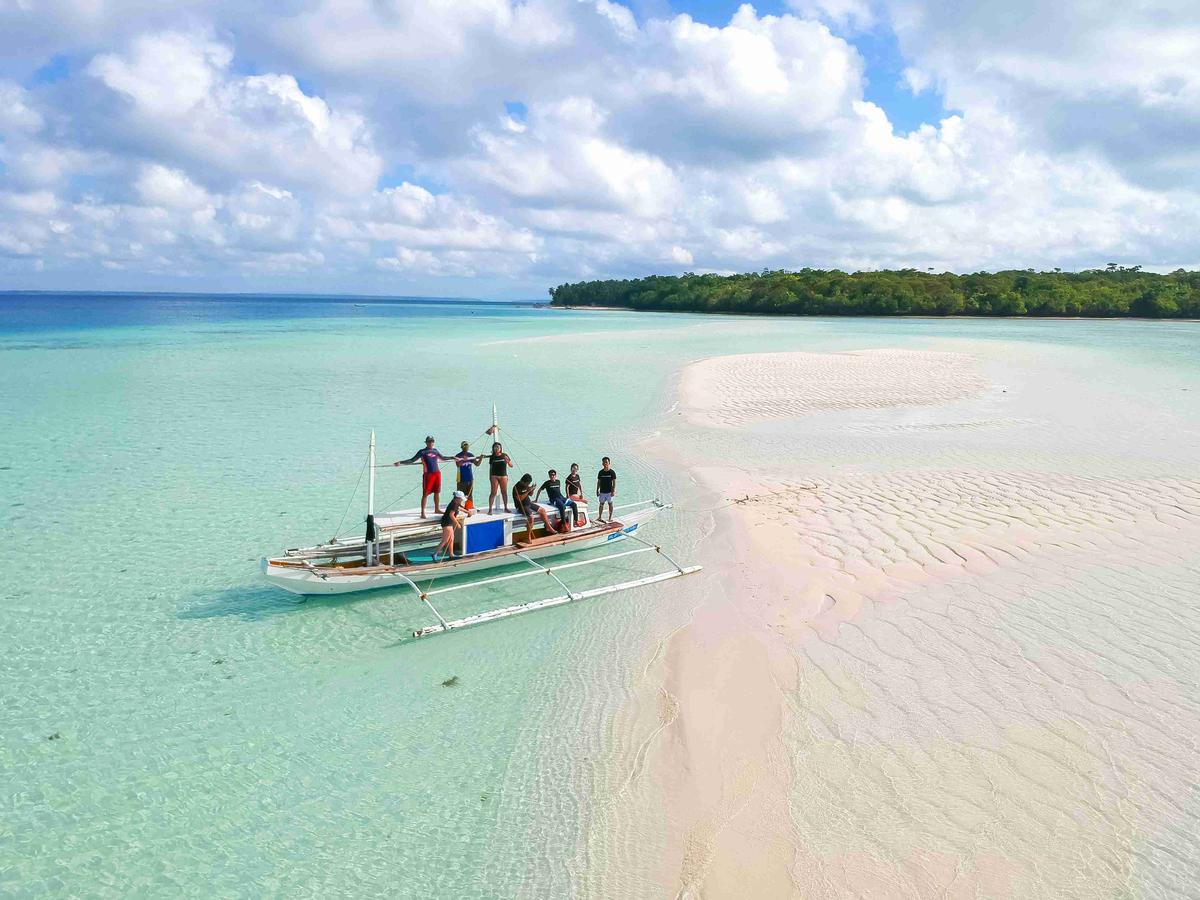 Boat and Tourists on Sandy Shoreline