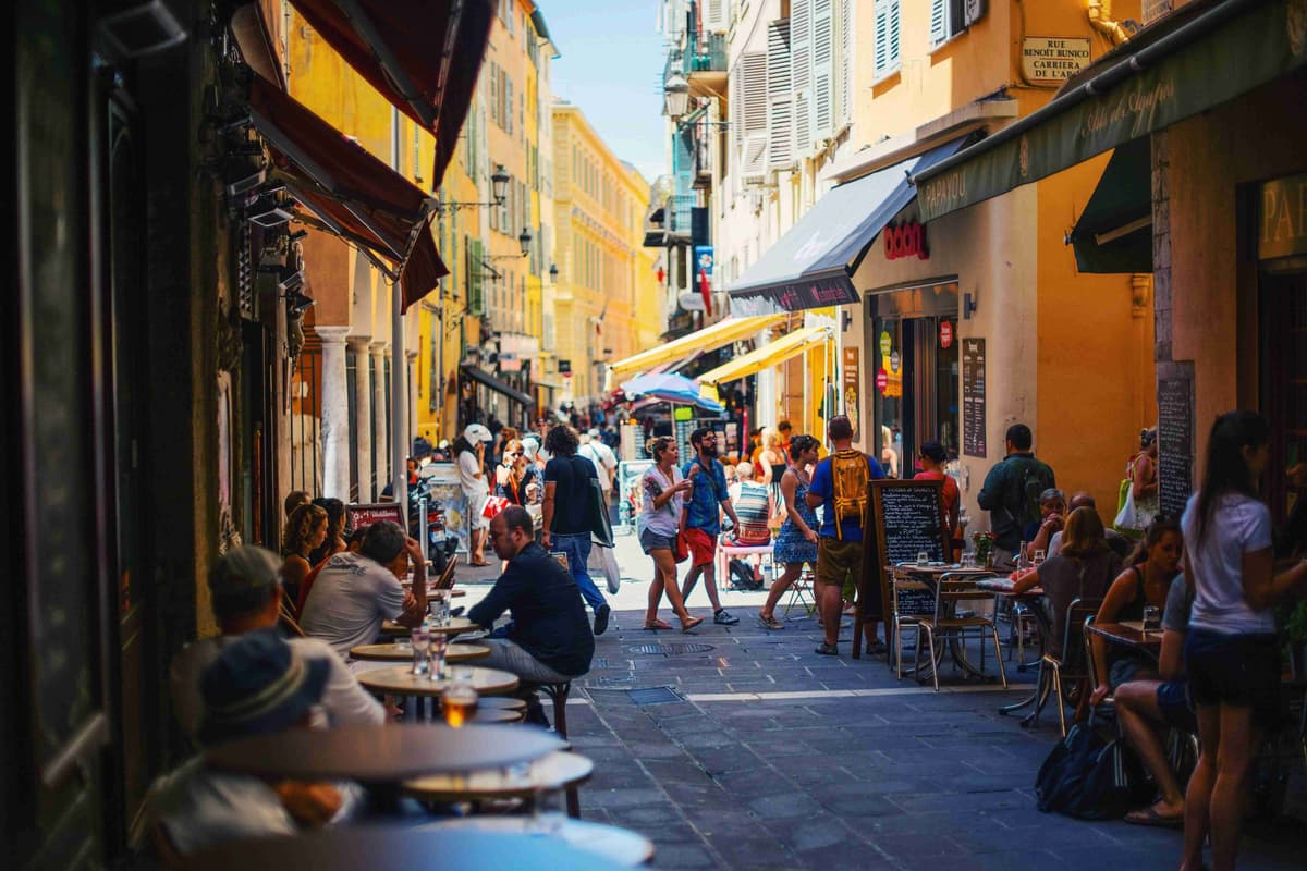 Bustling Street Scene in European City with Outdoor Cafes and Pedestrians