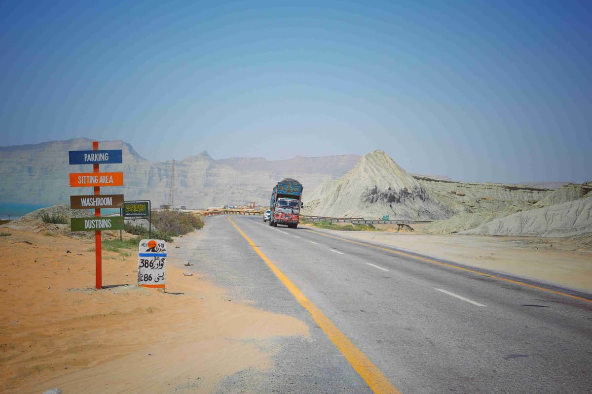 Camino del desierto con fondo montañoso y camión que pasa
