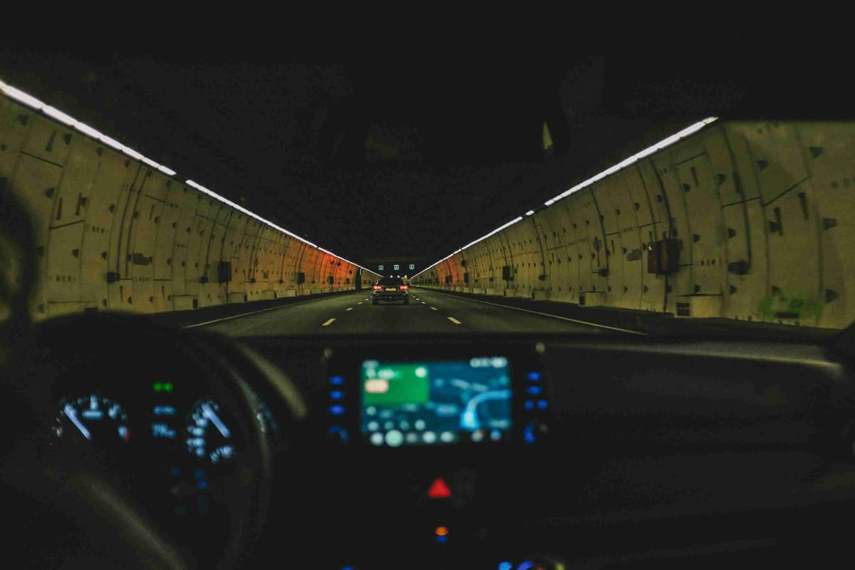 Вид из салона автомобиля, едущего по хорошо освещенному туннелю ночью