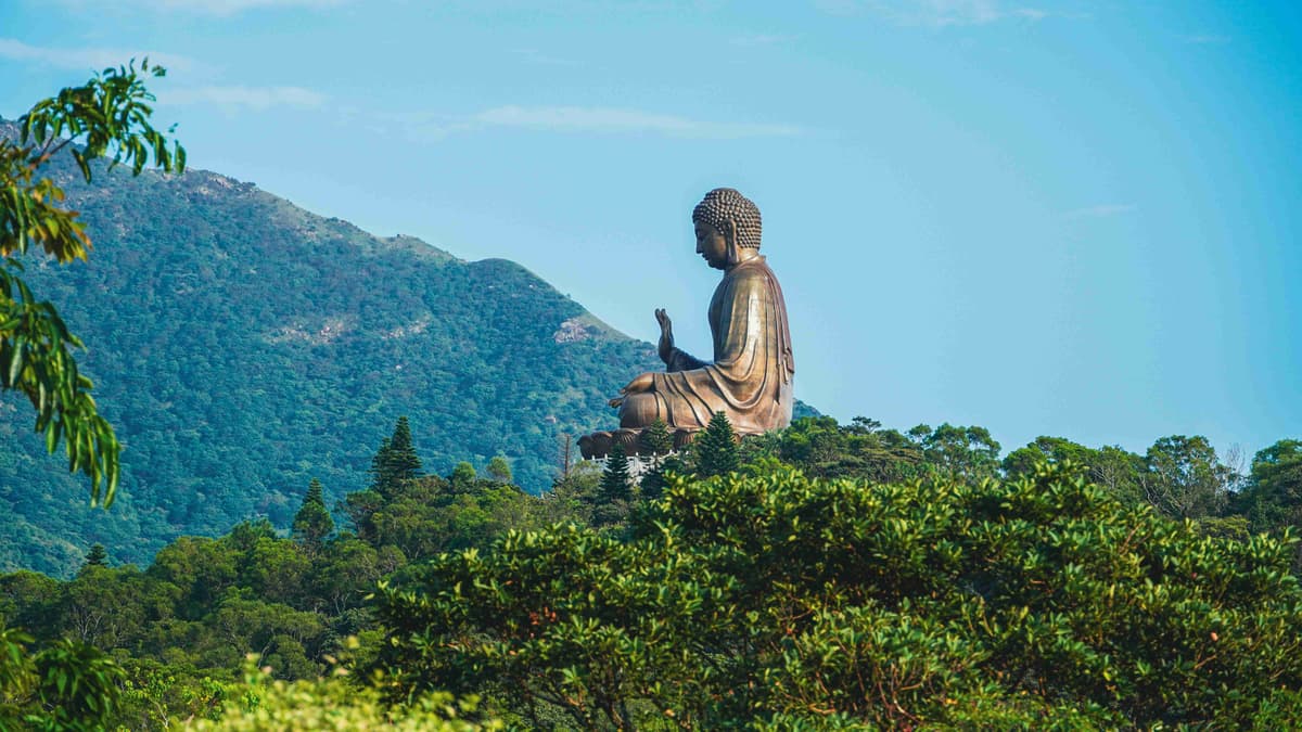 Giant Buddha Statue Amidst Green Mountains