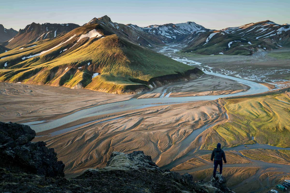 Турист с видом на дельту реки и горный хребет на закате