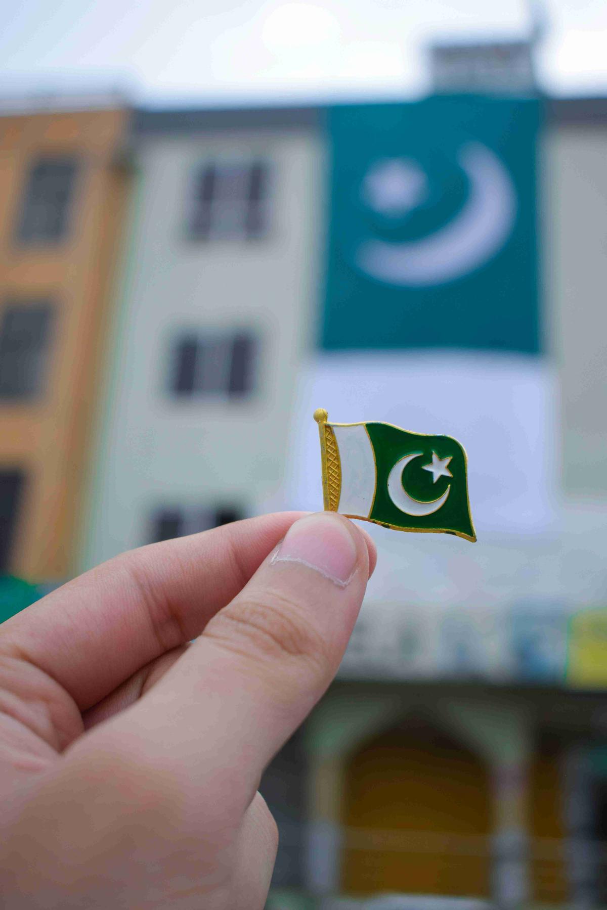 Holding Pakistani Flag Pin with Flag Backdrop