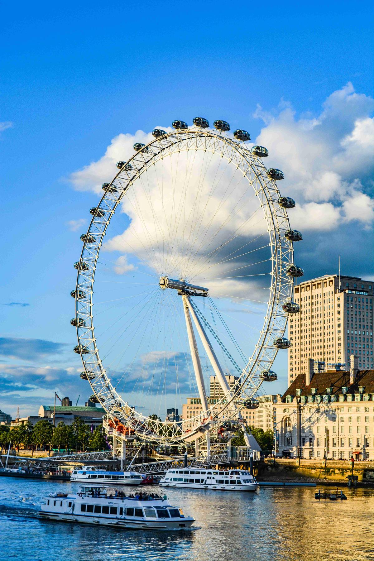 London Eye -maailmanpyörä aurinkoisena päivänä Thames-joen ja veneiden kanssa