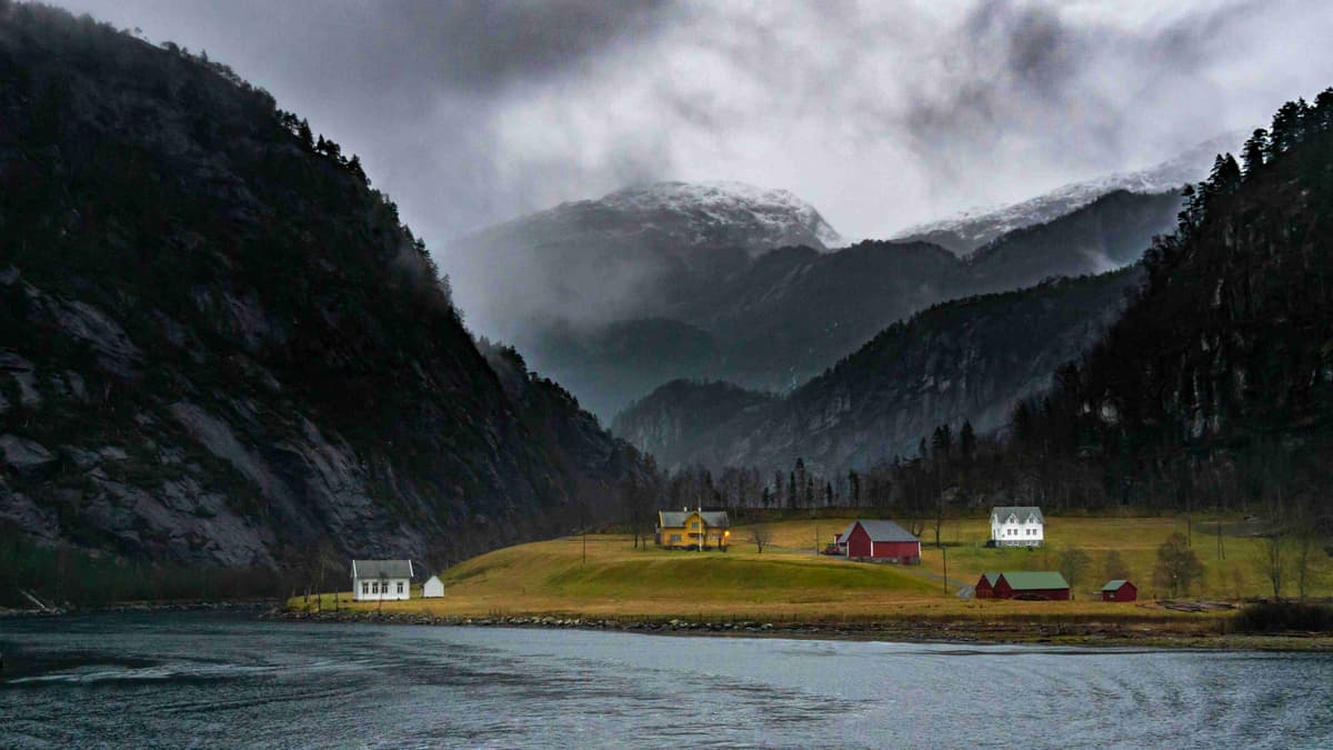 Fiorde enevoado com casas no penhasco Noruega