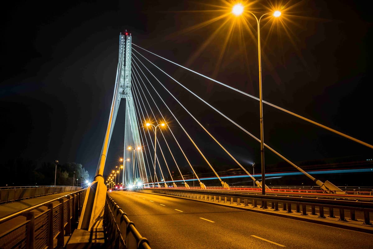 Vista nocturna del puente colgante iluminado con senderos de semáforo