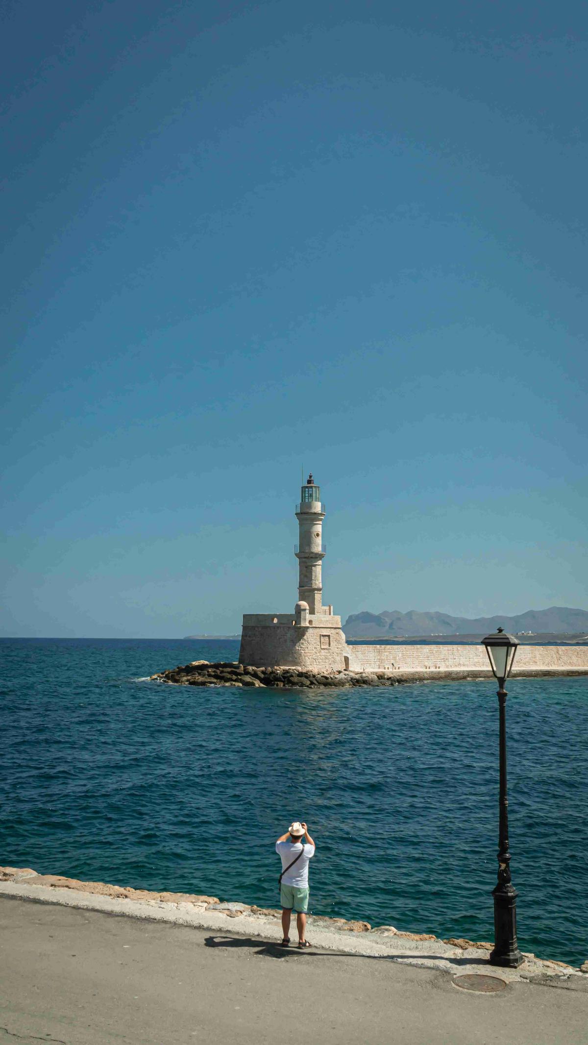 Человек, смотрящий на маяк у моря