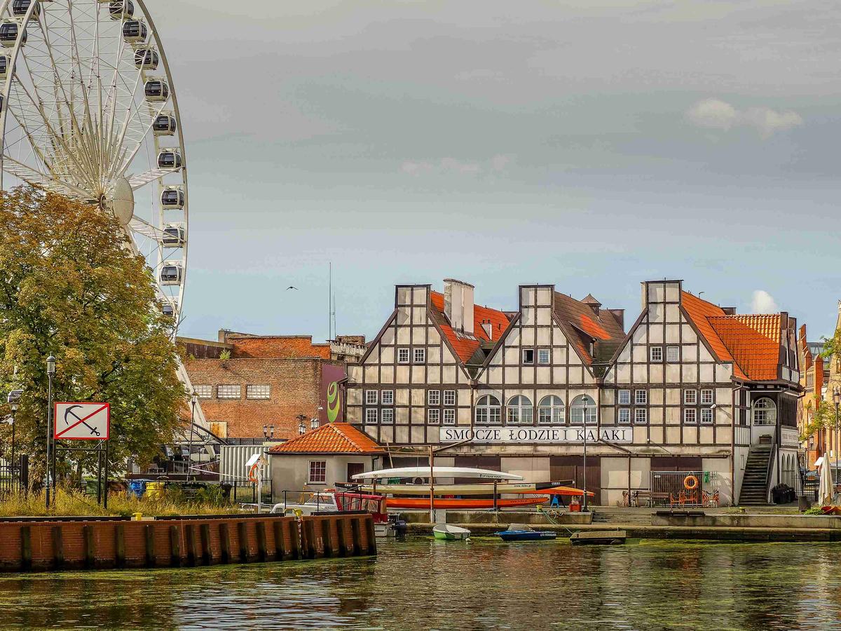 Blick auf den Fluss mit historischen Gebäuden und Riesenrad