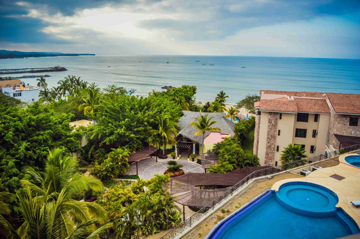 Vista do resort à beira-mar com piscinas e vegetação tropical