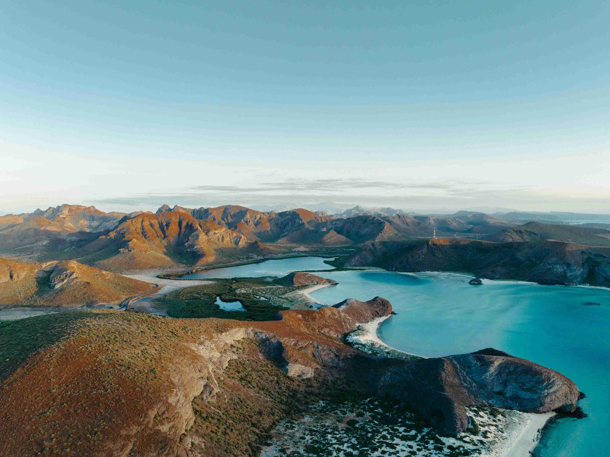 Γαλήνια παράκτια λιμνοθάλασσα με ορεινό φόντο στο λυκόφως