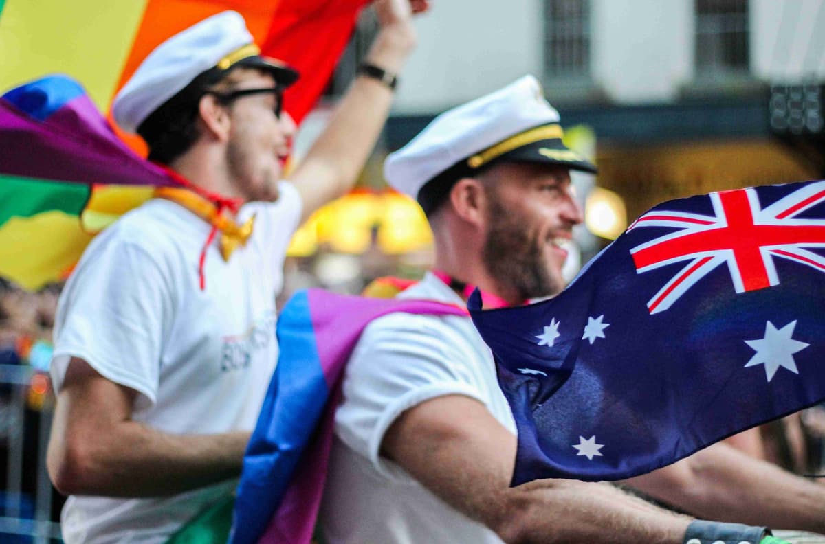 Two men in sailor hats waving australian flags.