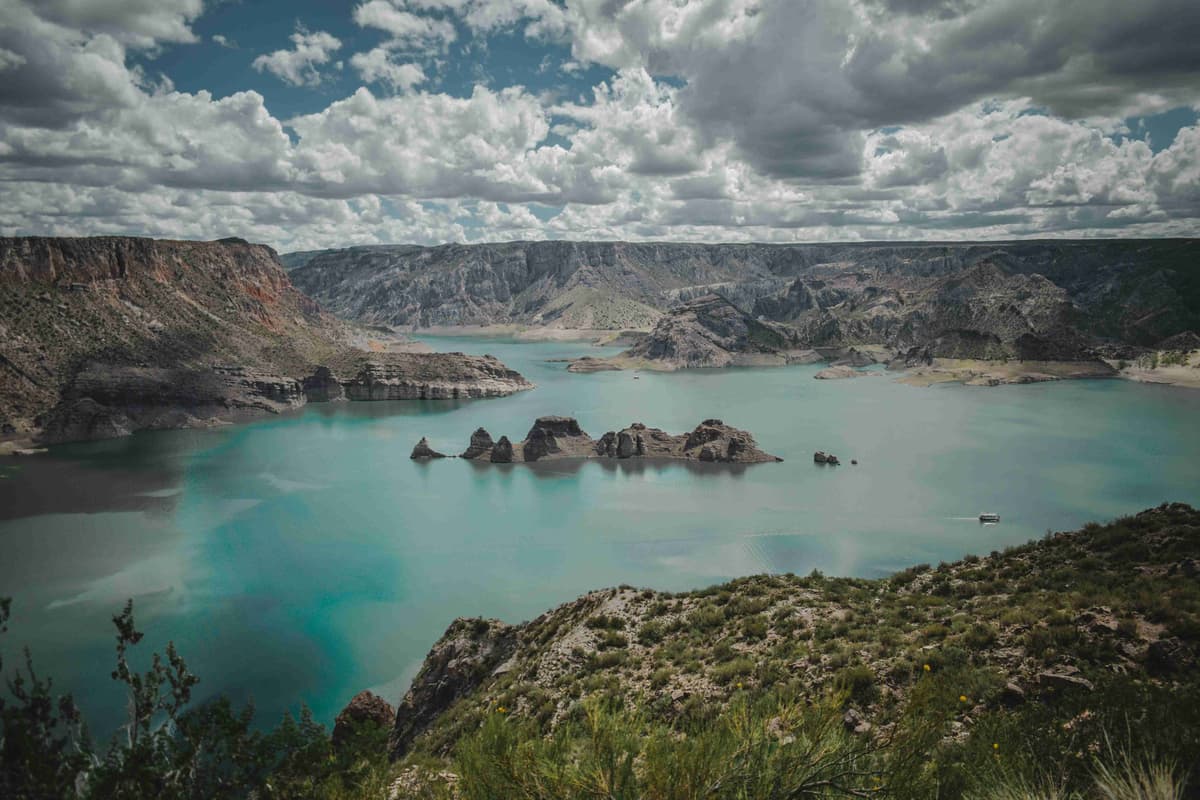 Turquoise Lake Surrounded by Rugged Cliffs and Cloudy Skies