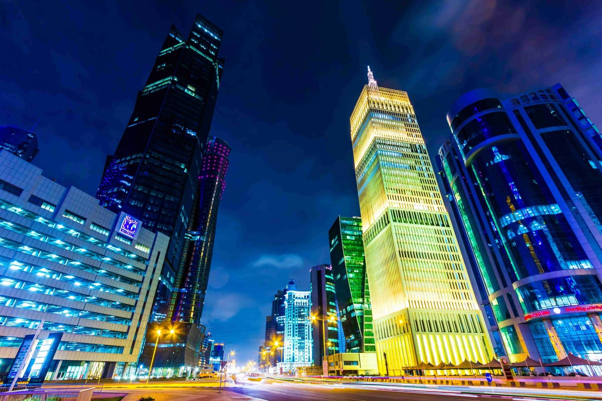 Оживен нощен градски пейзаж с осветени небостъргачи и оживена улица