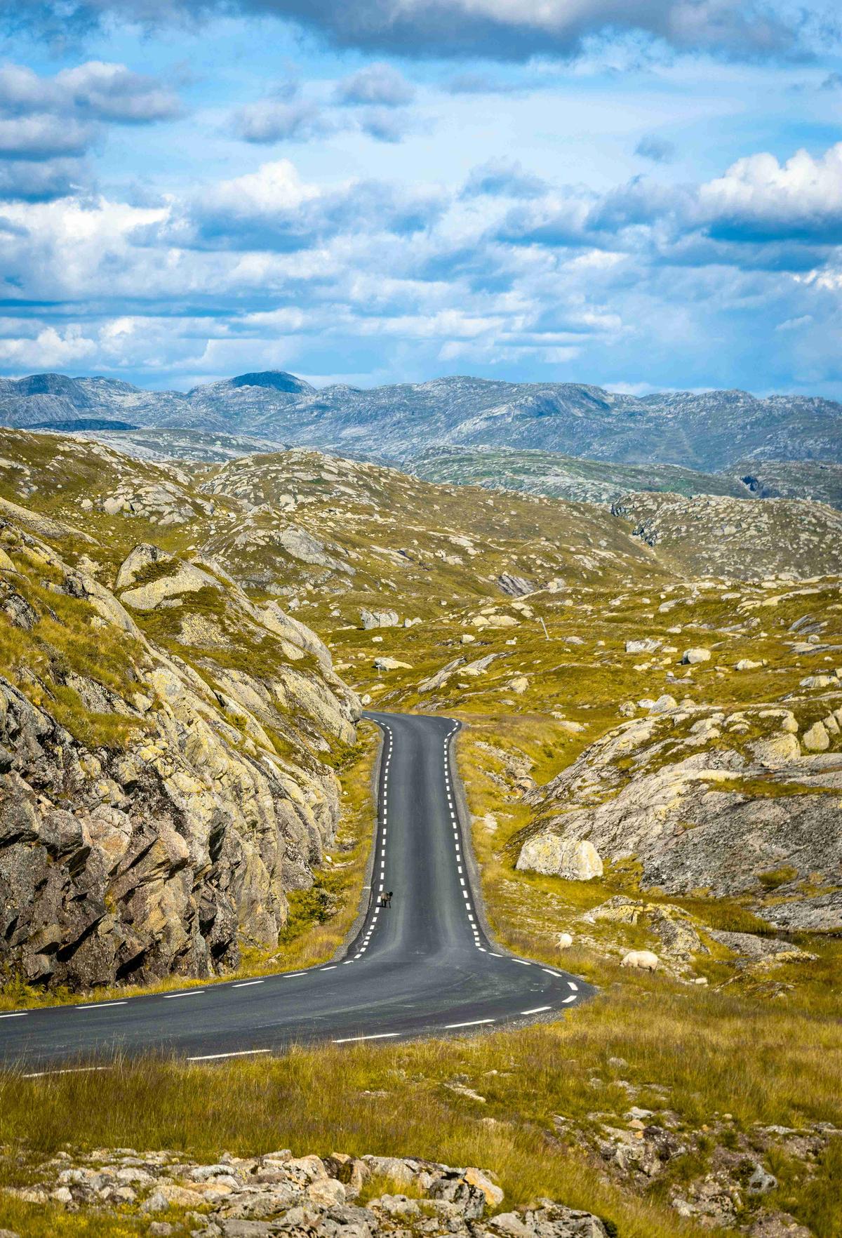 Звивиста гірська дорога з розсіяними хмарами