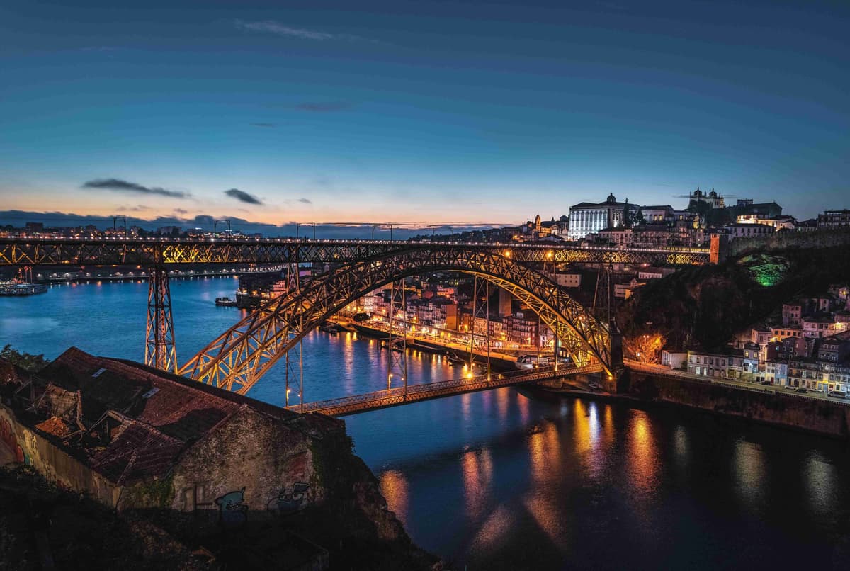 Atardecer sobre el puente Dom Luís I en Oporto, con paisaje urbano iluminado y río.