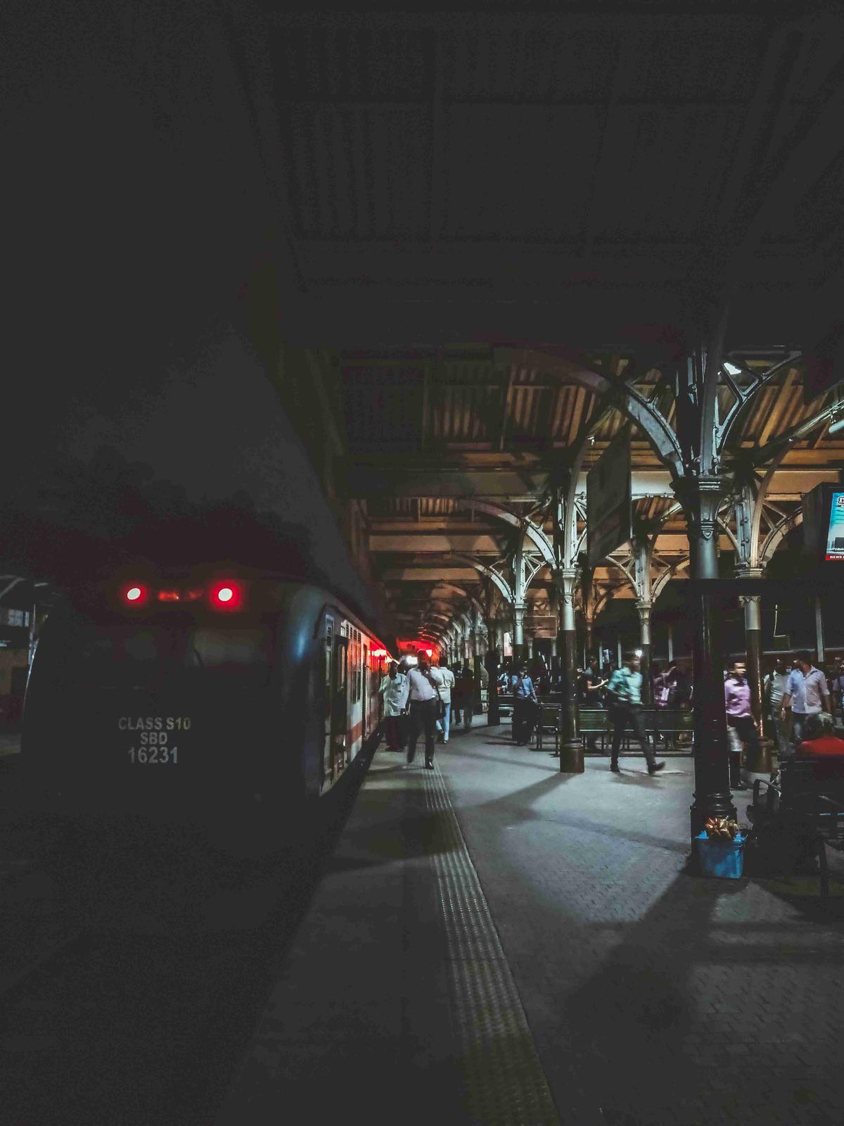 Estación de tren de noche con pasajeros embarcando