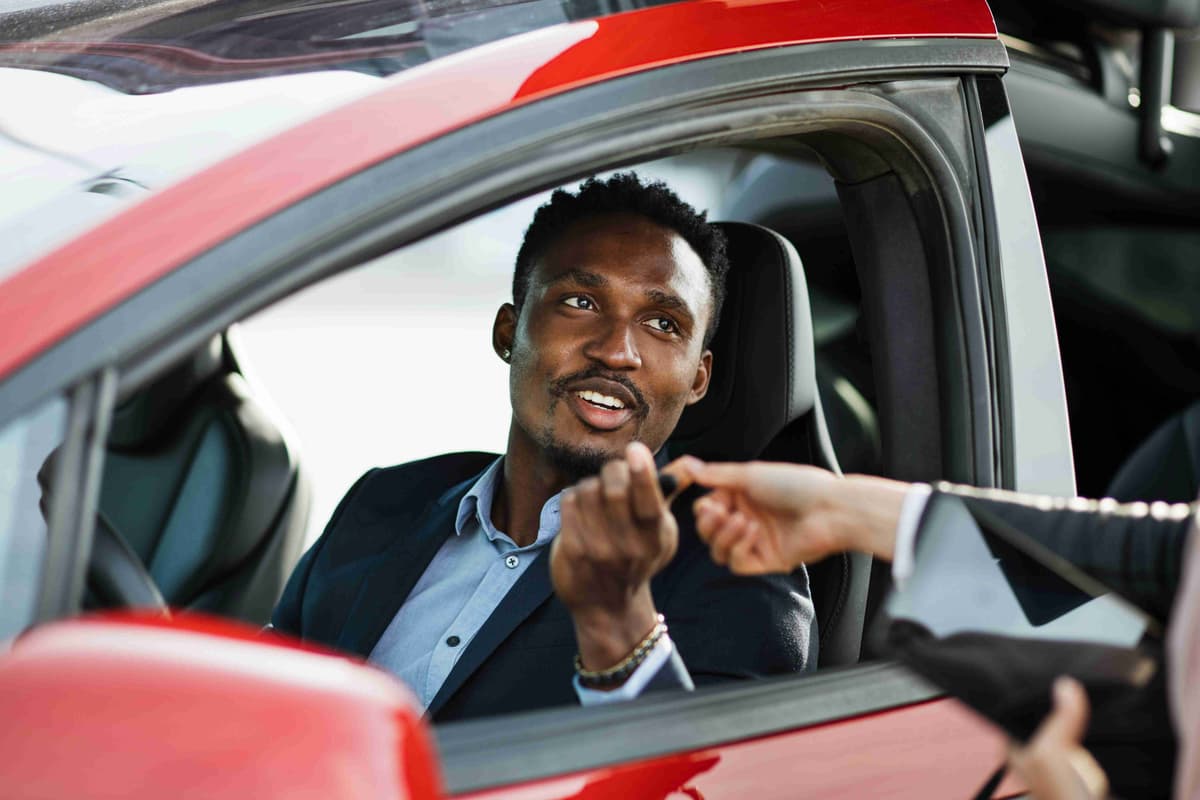 happy-african-man-sitting-inside-his-new-electric-car