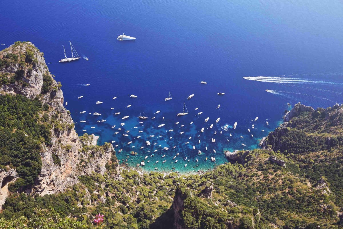 Pemandangan udara kapal layar berhampiran pantai berbatu Pulau Capri.