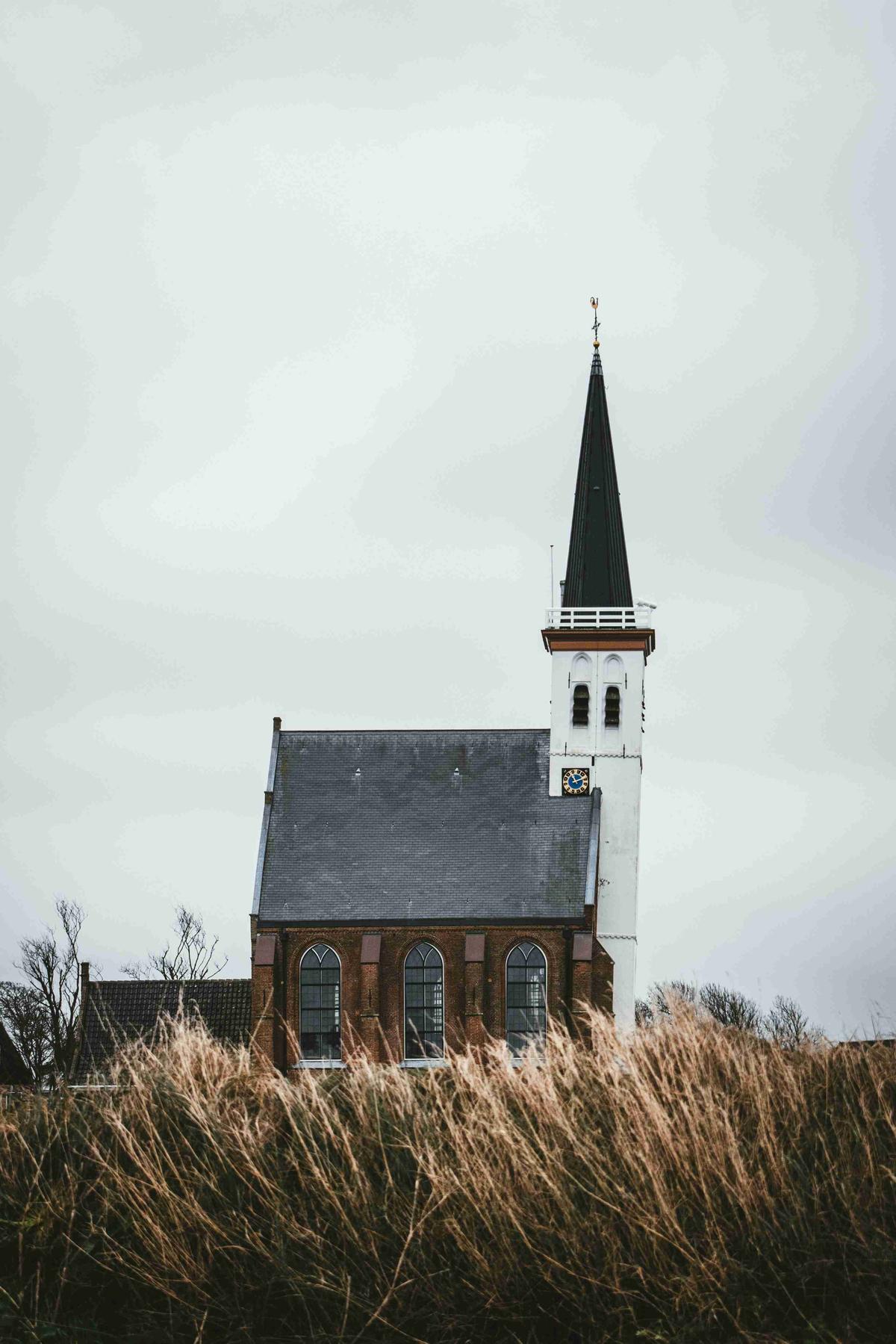 "Isolated Church with Spire on a Cloudy Day"