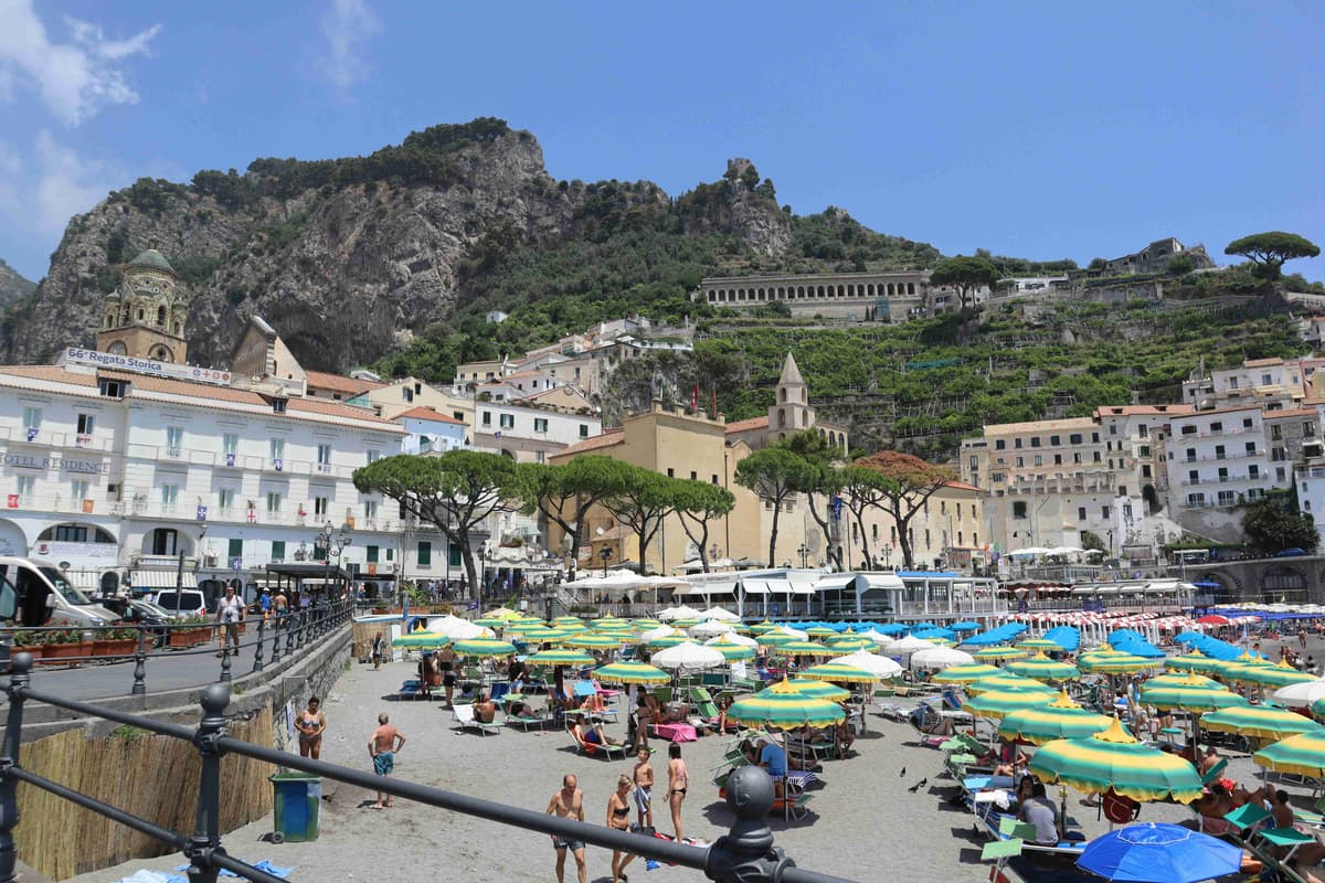 "Beachgoers at Amalfi Coast with Scenic Hillside View"