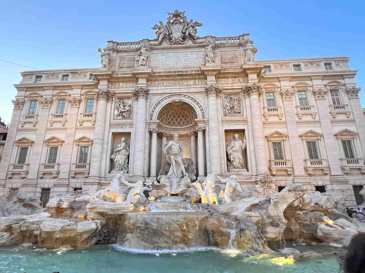 Trevi Fountain illuminated at dusk with sculptures and flowing water.