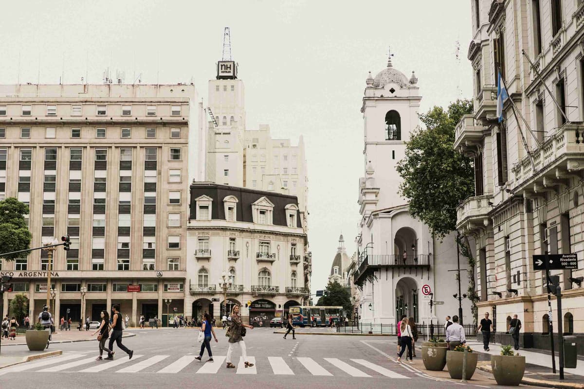 woman-crossing-pedestrian-lane-between-tall-buildings