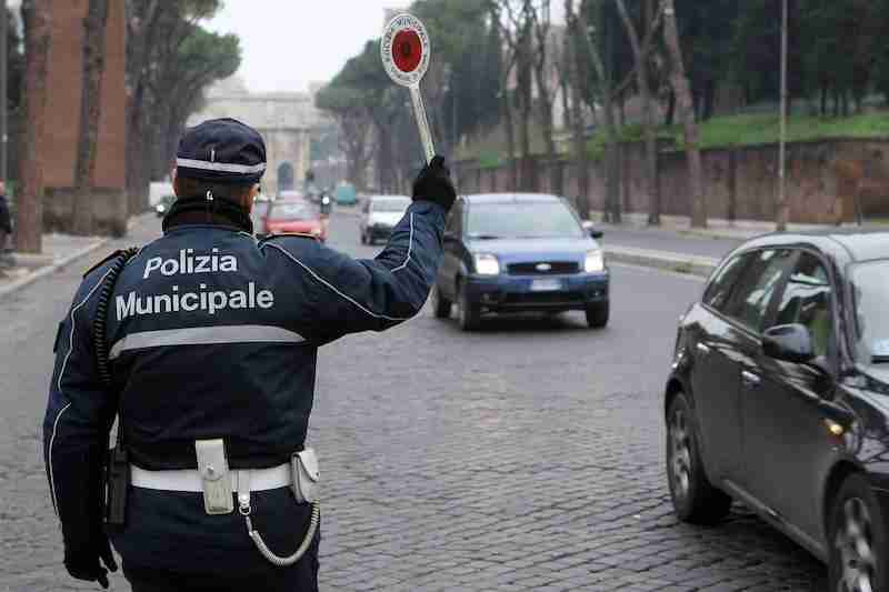 Italian 'Polizia Municipale' officer holding a stop sign on a street.