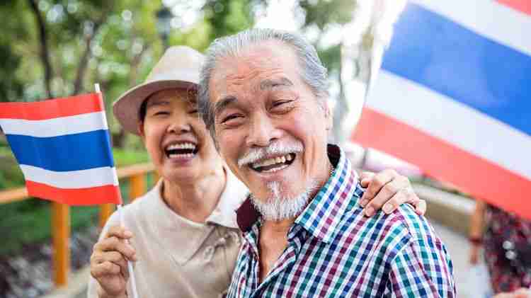 two old people holding the flag of Thailand.