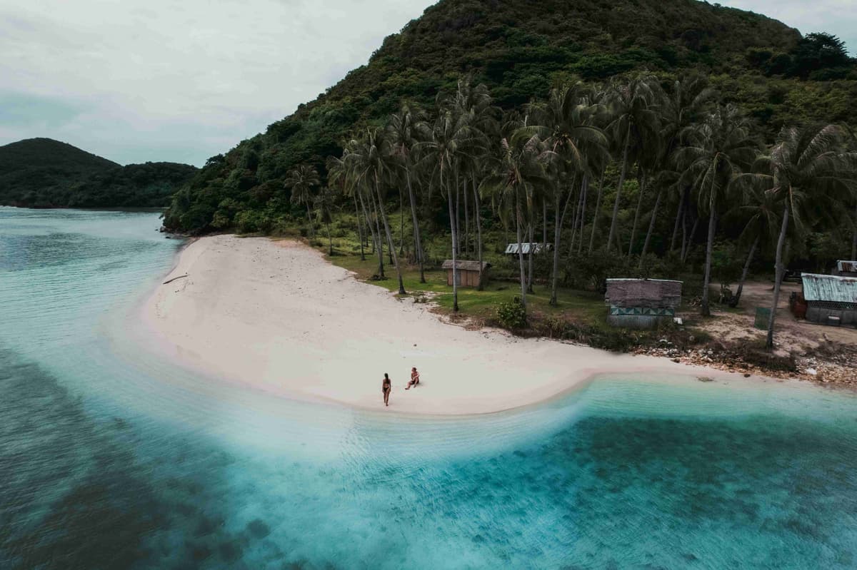 two people are walking on a beach
