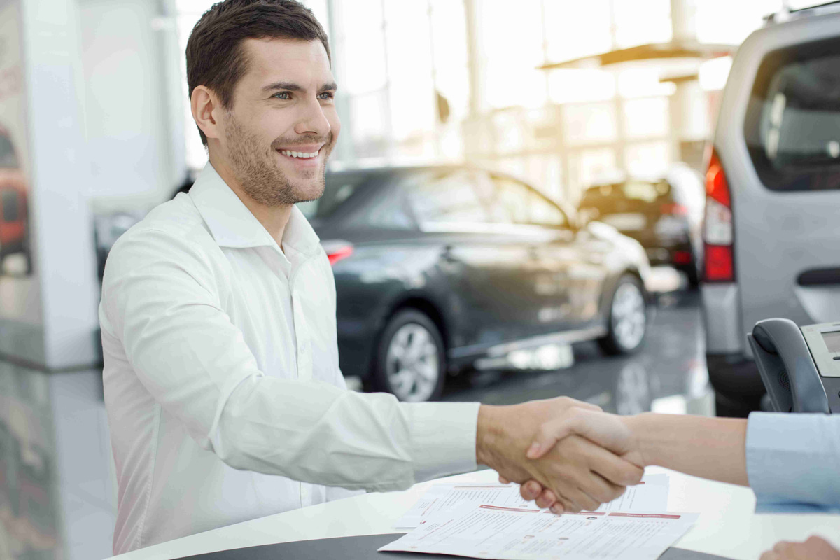 Car Salesman Shaking Hand with Customer in Dealership