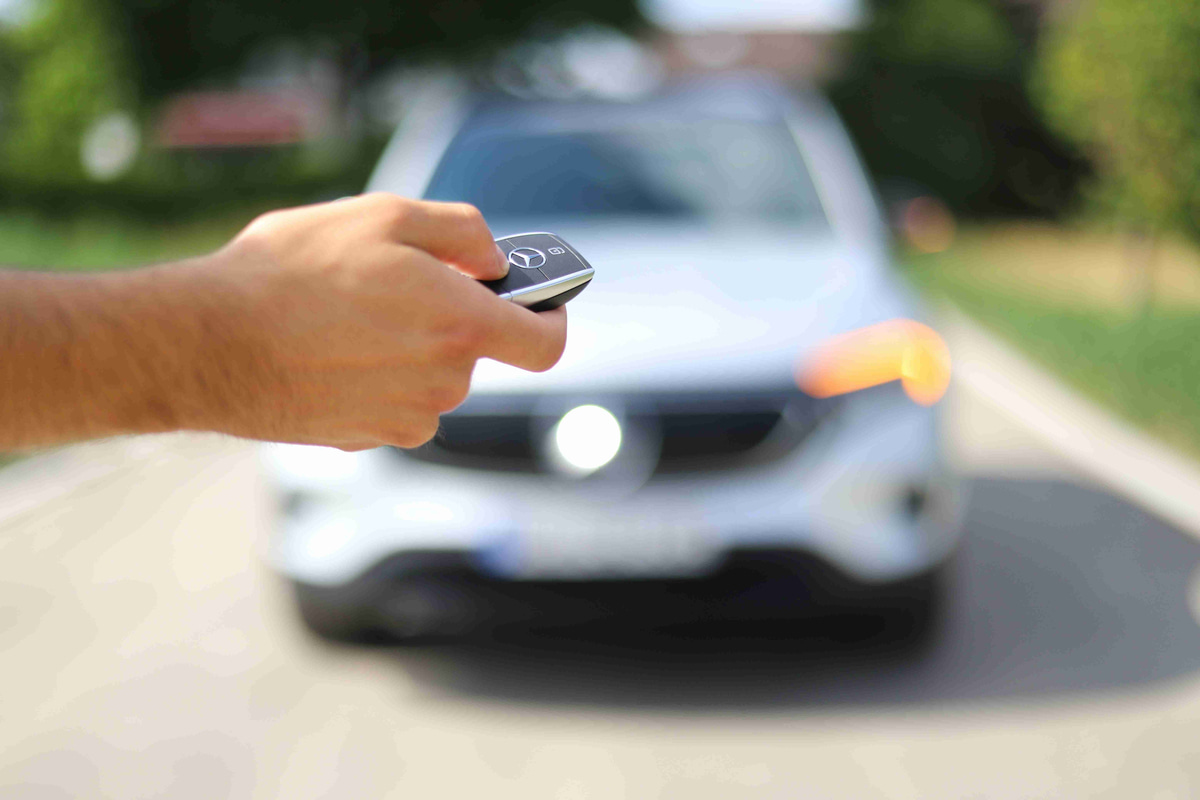Hand_Holding_Car_Key_Fob_with_Car_in_Background