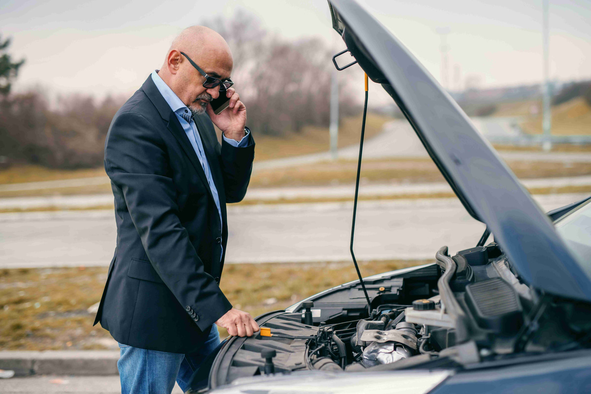 man-checking-car-engine-while-on-phone