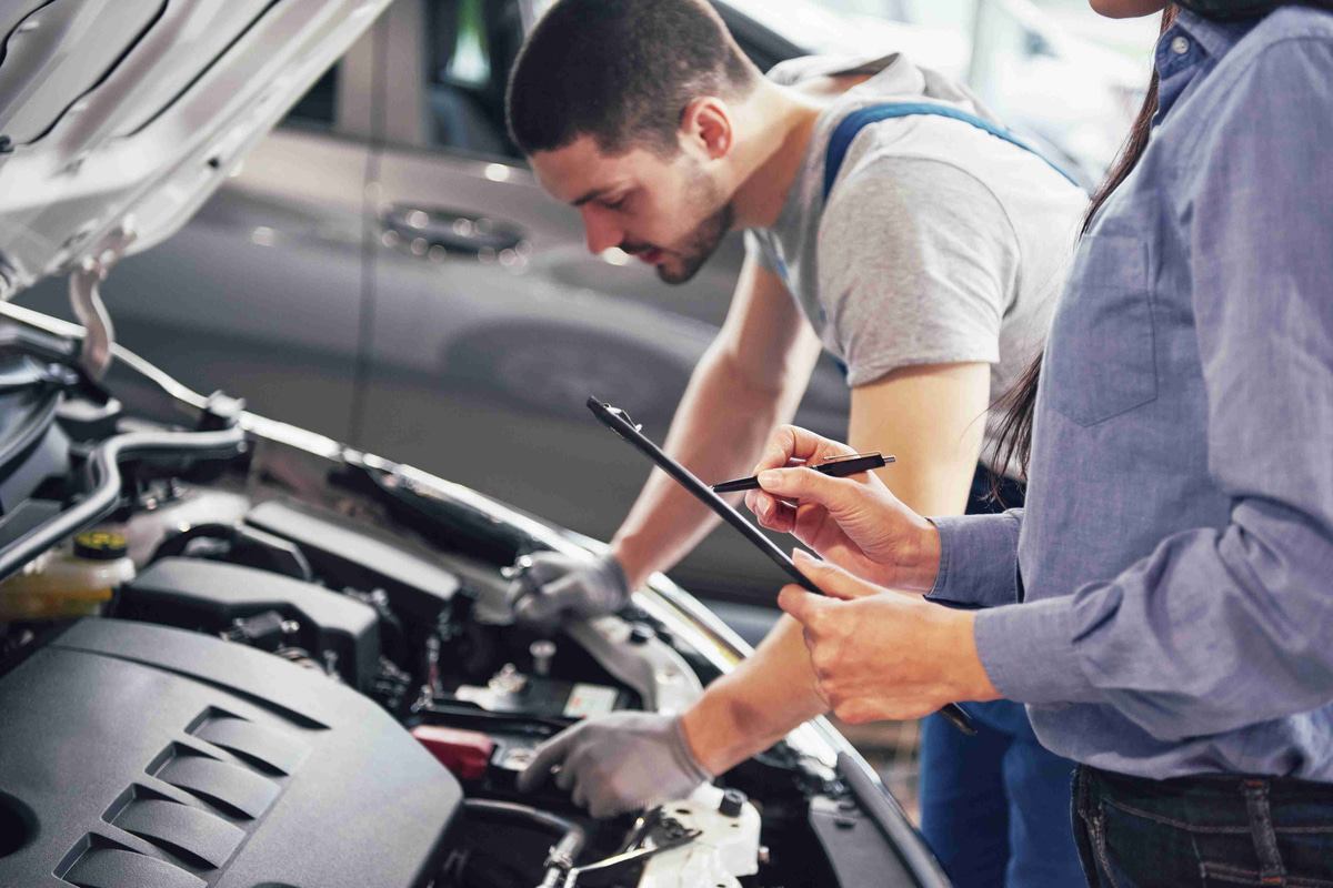 man-mechanic-woman-customer-look-car-hood-discuss-repairs