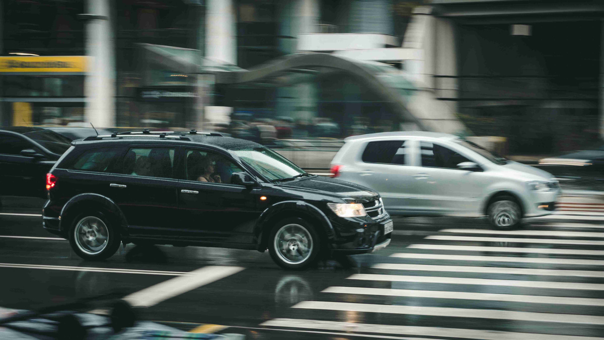 black suv beside grey auv crossing the pedestrian line during daytime
